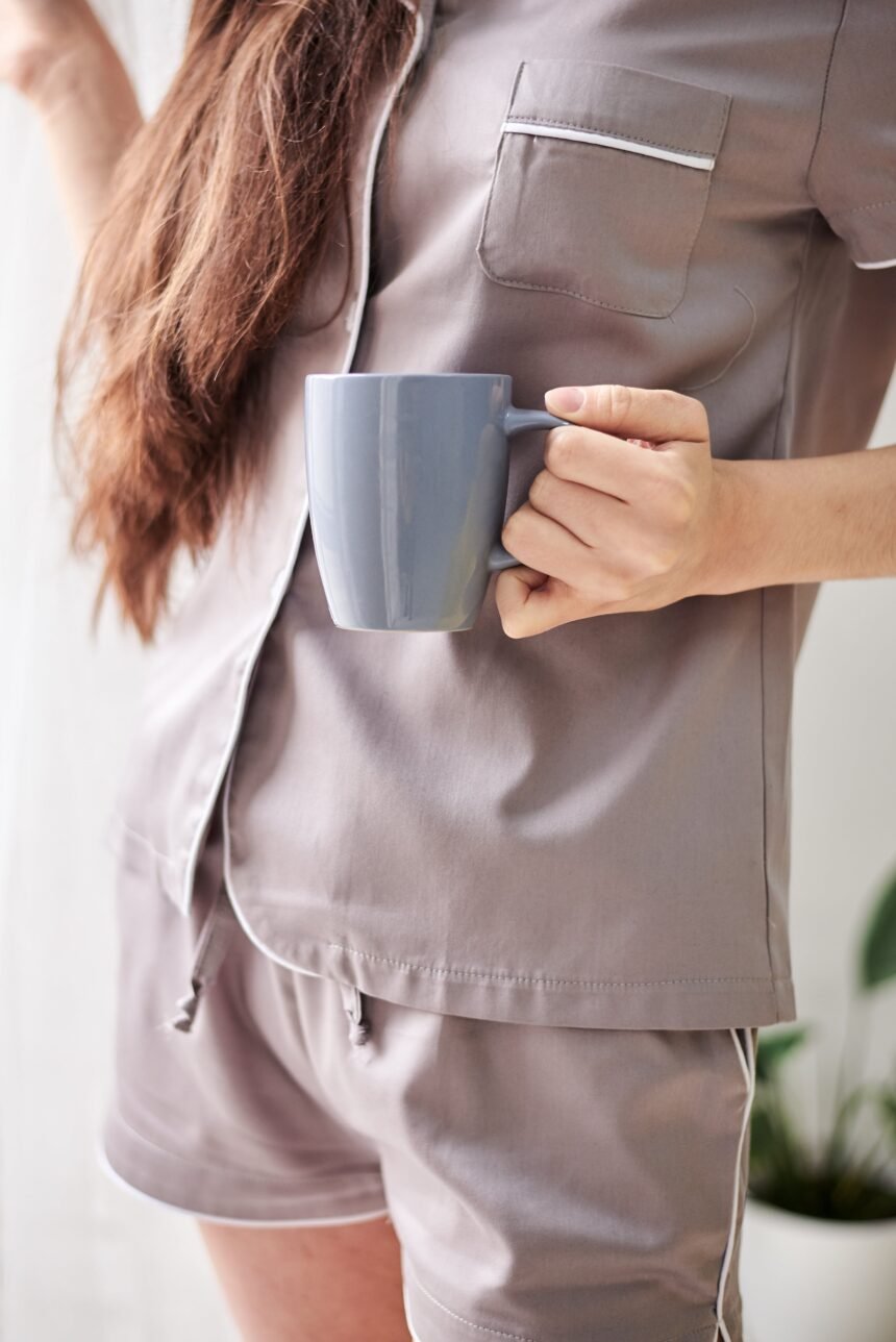 Webstory - Cha verde e perda de peso  NAO USAR APOS ESSA DATA 10-10-2024 EM CASO DE DUVIDA CONSULTE A FOTOGRAFIA  Young pretty slim brunette woman, wearing grey satin pajamas,, holding grey coffee cup mug, drinking. Close-up picture of woman's hand, holding coffee mug in the morning. photo Natalia/adobe.stock